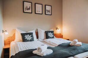 A double bed with white bedding and a dark green throw, two nightstands with wall-mounted lamps, and three framed pictures on the wall. - Family-friendly apartment with a terrace and a cozy living area (Sankt Michael im Lungau)