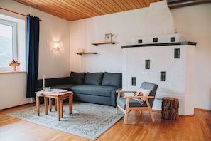 A cozy living room with a grey sofa, a wooden coffee table, a chair, and a decorative castle wall. - Family-friendly apartment with a terrace and a cozy living area (Sankt Michael im Lungau)
