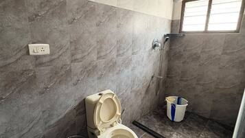 Een badkamer met toilet, douche en een raam.