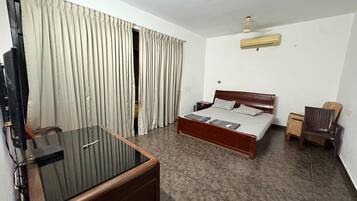 Een hotelkamer met een bed, een bureau, een stoel, een televisie en gordijnen.