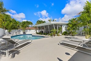 A pool area with lounge chairs, a covered patio, and palm trees. - Barrier Island 2 Bedroom/1 Bath. Walk to the Beach (Fort Lauderdale)
