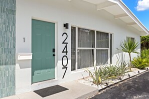 A white building with a teal door and windows, numbered 2407. - Studio on the Barrier Island. Walk to the Beach (Fort Lauderdale)
