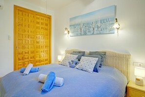 A bedroom with a bed, a wooden door, a painting, and a nightstand with a lamp. - Casa La Calma – Holiday Home with Private Pool (el Cim del Sol)