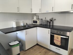 A modern kitchen with white cabinets, a black countertop, a microwave, a kettle, and a stainless steel oven. - 2 Bed Duplex in Castle Harbour C207' with Shared Pool, Wi-Fi and Air Conditioning (Los Cristianos)
