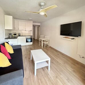 A modern living space with a kitchen, dining area, and a flat-screen TV mounted on the wall. - 2 Bed Duplex in Castle Harbour C207' with Shared Pool, Wi-Fi and Air Conditioning (Los Cristianos)
