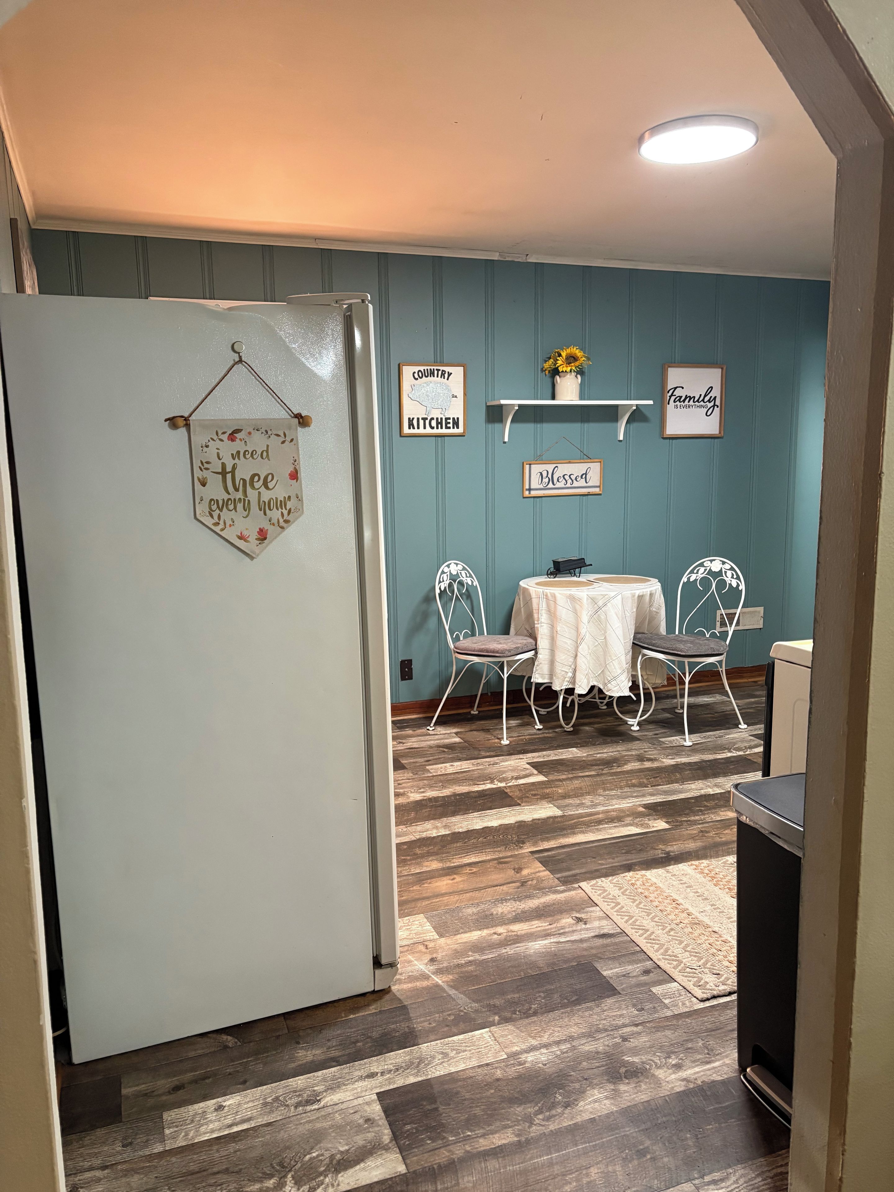 A kitchen with a white refrigerator, a dining table with chairs, and a wall with decorative items.