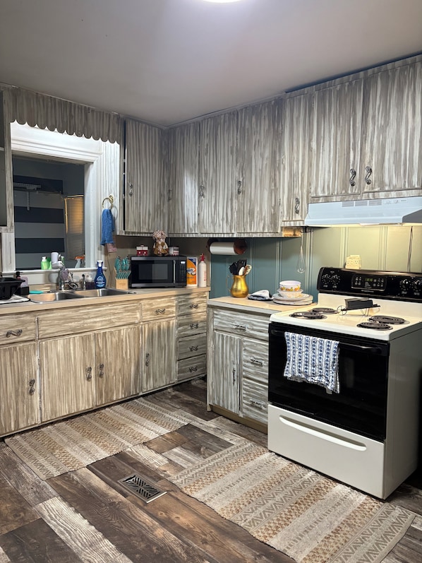 A kitchen with wooden cabinets, a microwave, a stove, and a patterned rug.