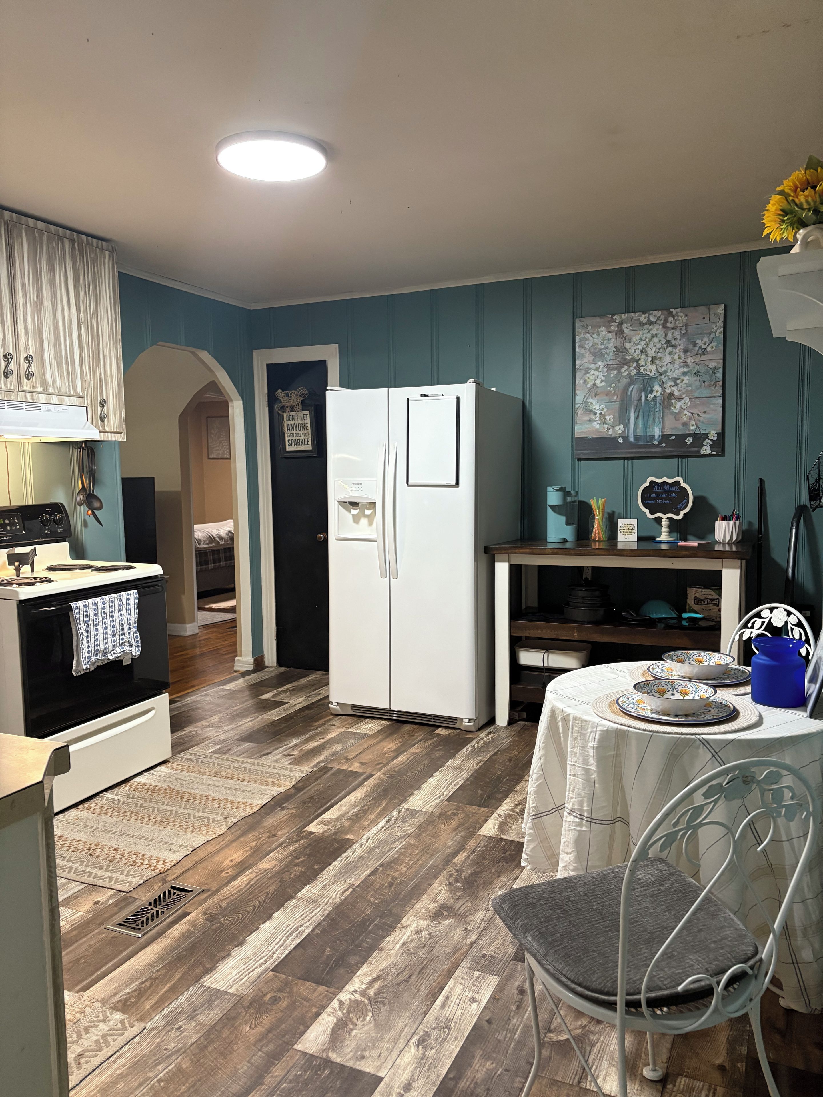 A compact kitchen with a refrigerator, stove, and dining area with a table and chairs.