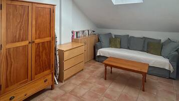 A room with a wooden wardrobe, a sofa, a small table, and a skylight.