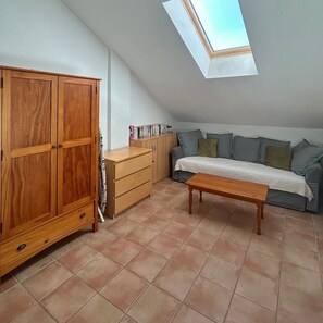 Ein Zimmer mit einem Holzschrank, einer Couch, einem kleinen Tisch und einem Oberlicht.