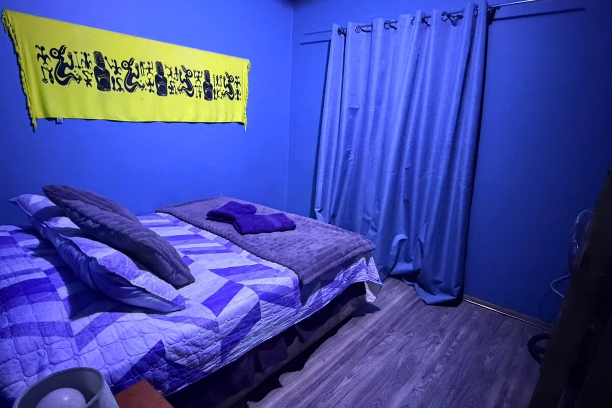 A room with a bed, a curtain, and a wall hanging.
