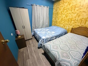 A bedroom with two beds, a wardrobe, a curtain, and a wall with a textured pattern. - CABAÑA FAMILIAR 3 HABITACIONES (Hanga Roa)