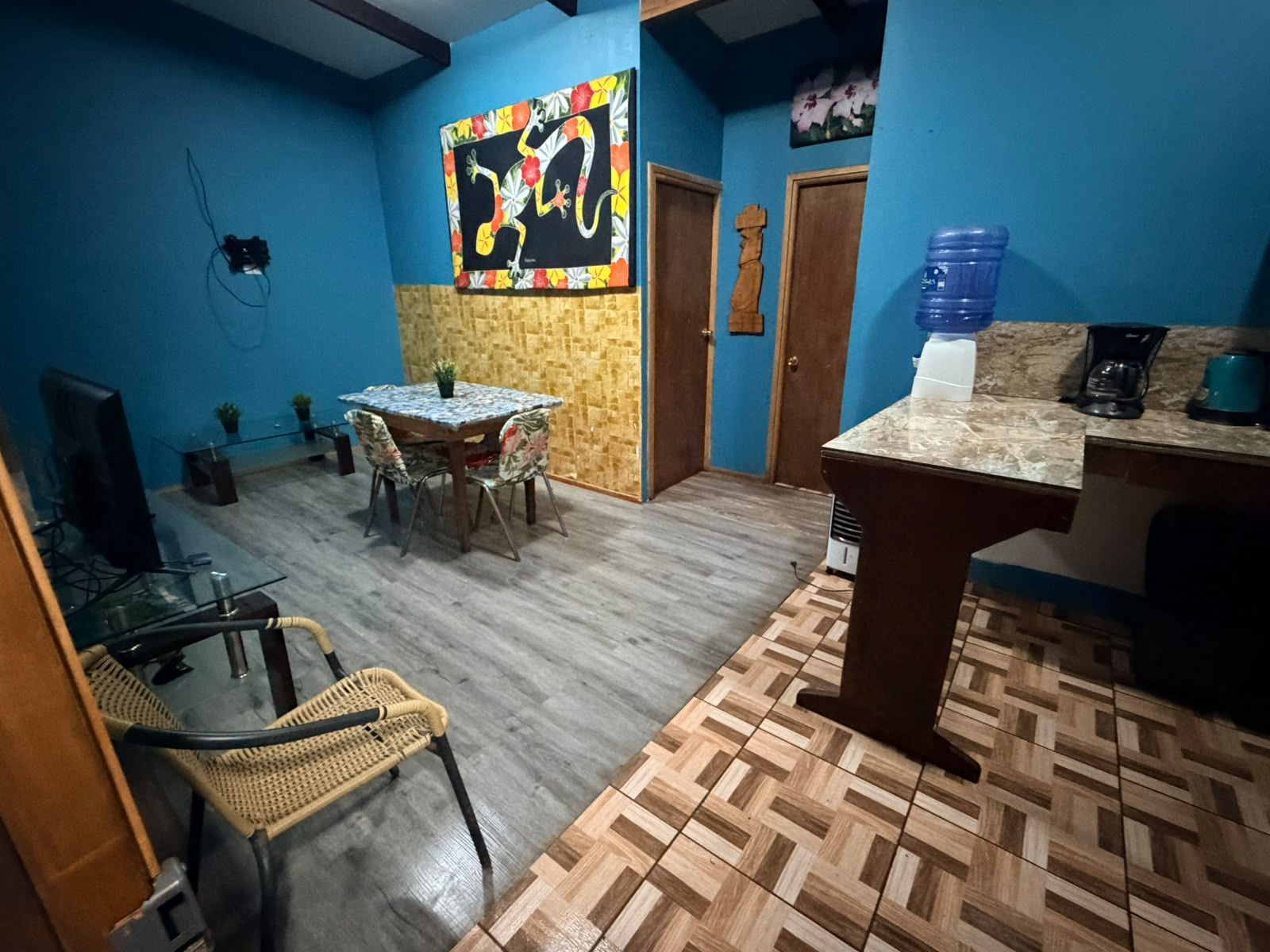 A room with a dining table, chairs, a television, and a water dispenser.