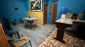 A room with a dining table, chairs, a television, and a water dispenser.