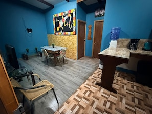 Una habitación con una mesa de comedor, sillas, un televisor y un dispensador de agua.