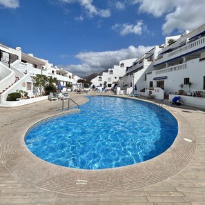 A swimming pool with a tiled edge, surrounded by white buildings with balconies and steps leading up to them. - Vacation Home 'Studio Port Royal K007' with Wi-Fi (Tenereif)