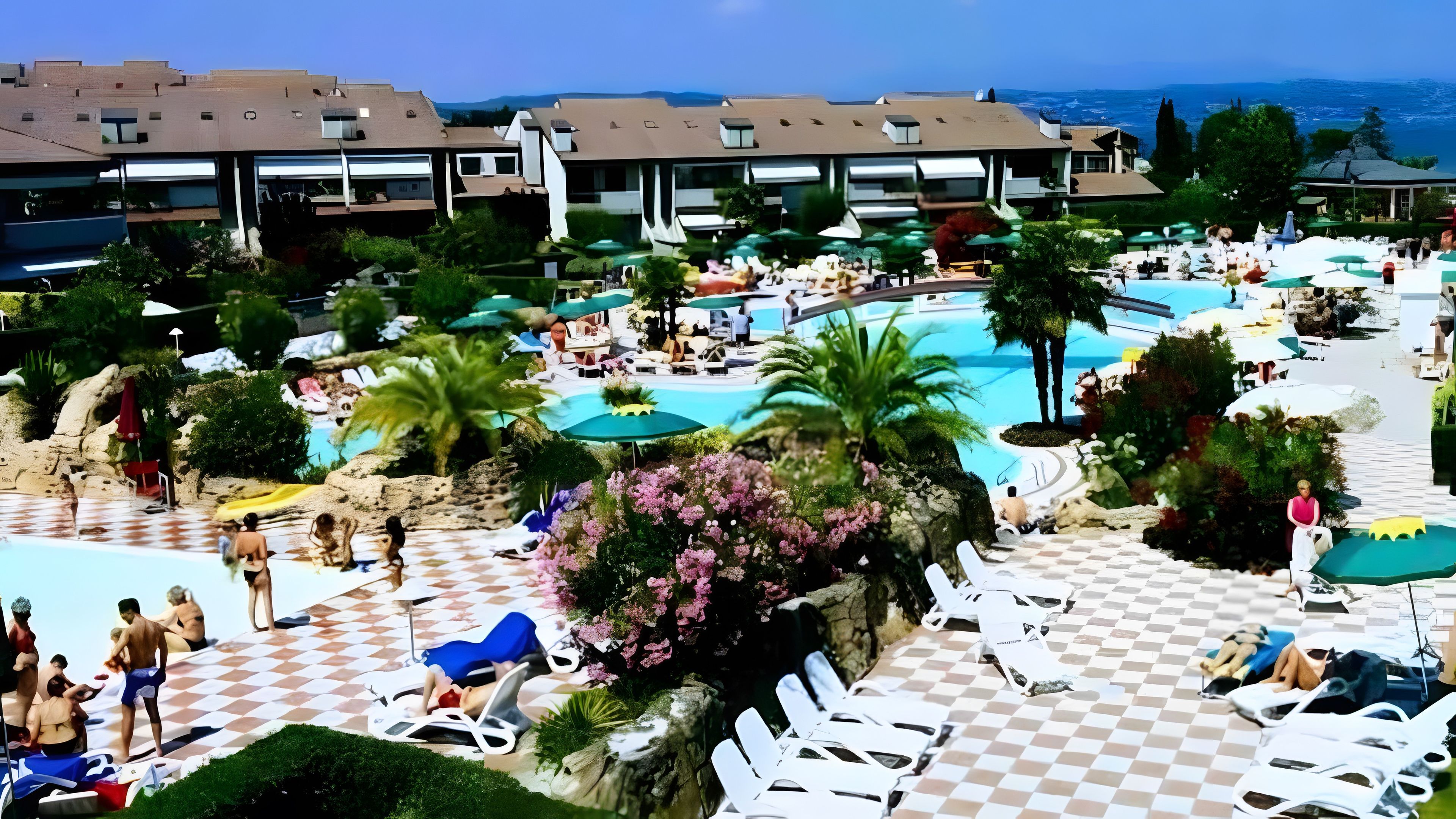 Un complexe hôtelier doté d’une piscine, de chaises longues et offrant une vue sur l’océan.