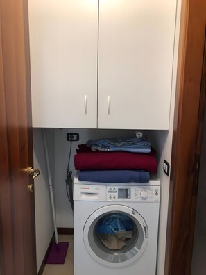 A compact laundry area with a washing machine and a cabinet above it. - Apartment 'Talla' with Shared Pool, Wi-Fi and Air Conditioning (Desenzano del Garda)