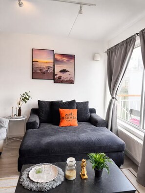 Un salon moderne avec un canapé foncé, une table basse agrémentée d’objets décoratifs et deux tableaux encadrés accrochés au mur.