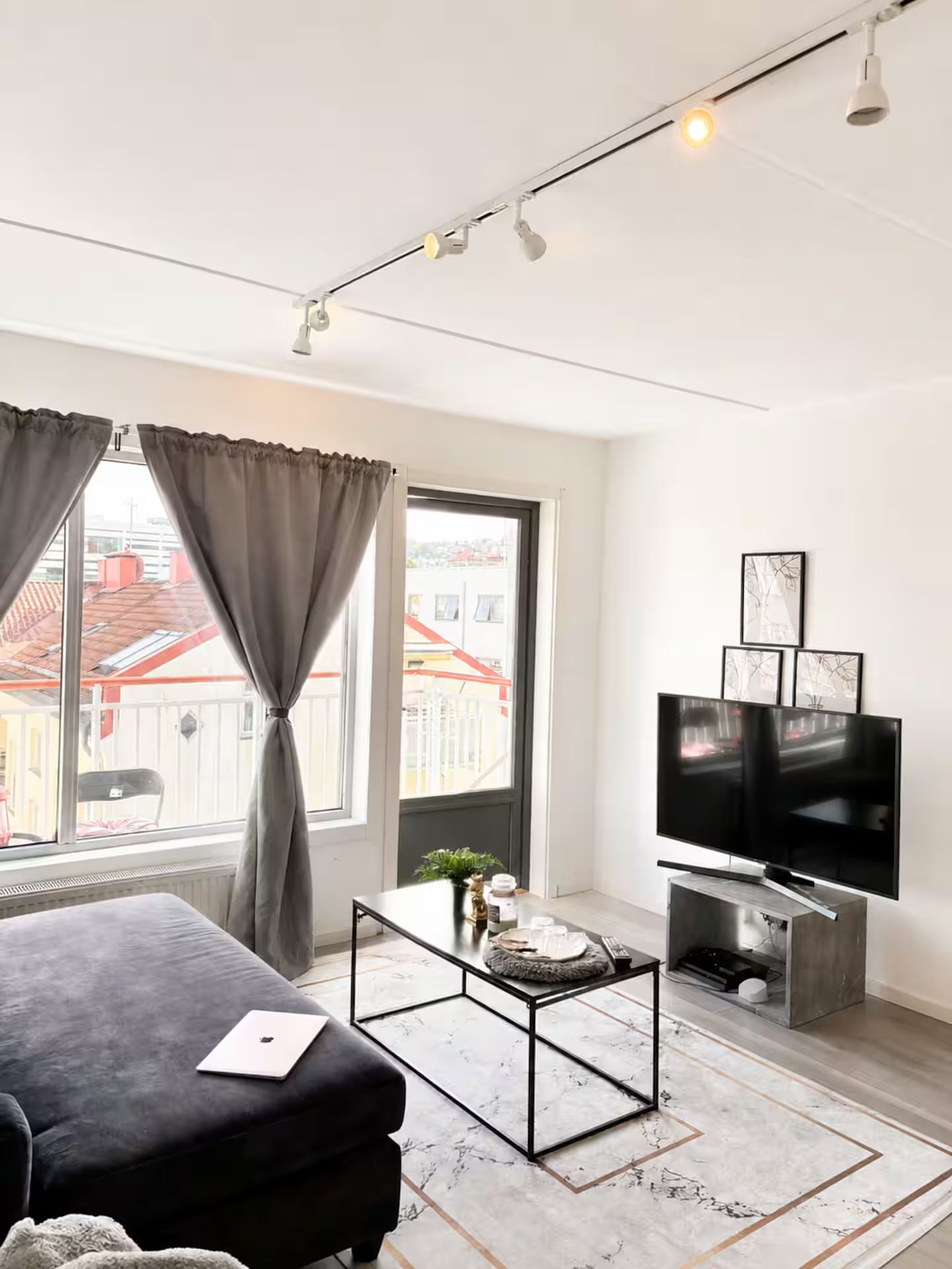 Ett modernt vardagsrum med en soffa, ett soffbord, en tv och konstverk på väggen.