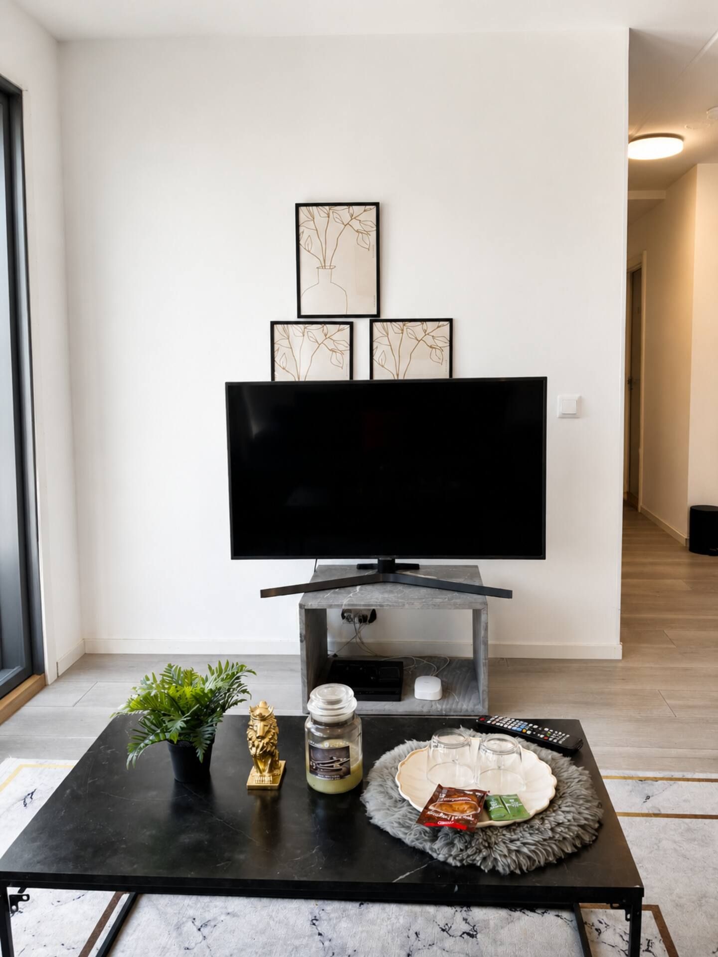 Een moderne woonkamer met een flatscreen televisie, een open haard en een salontafel met decoratieve objecten.