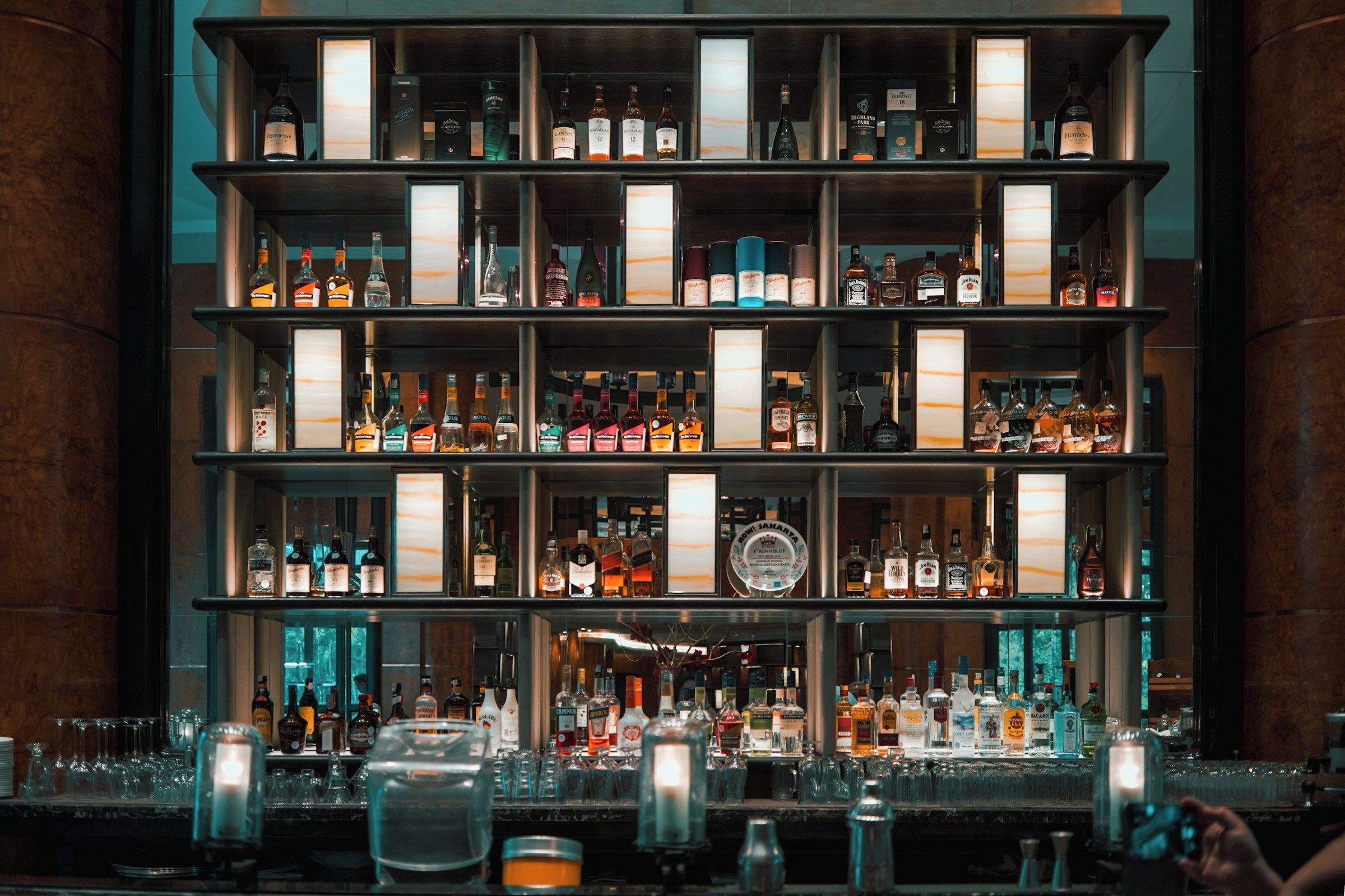 A bar with multiple shelves stocked with various liquor bottles and glasses.