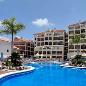 Resort com piscina, várias varandas e palmeiras.