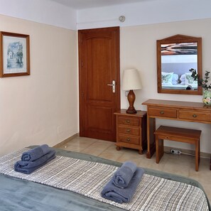 A hotel room with a bed, a wooden dresser, a mirror, a lamp, and a painting on the wall. - Vacation Home 'Apt with Ocean View San Blas K104' with Wi-Fi (Golf del Sur)