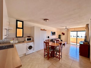 A compact living space with a kitchenette, dining area, and a view through a sliding door. - Vacation Home 'Apt with Ocean View San Blas K104' with Wi-Fi (Golf del Sur)