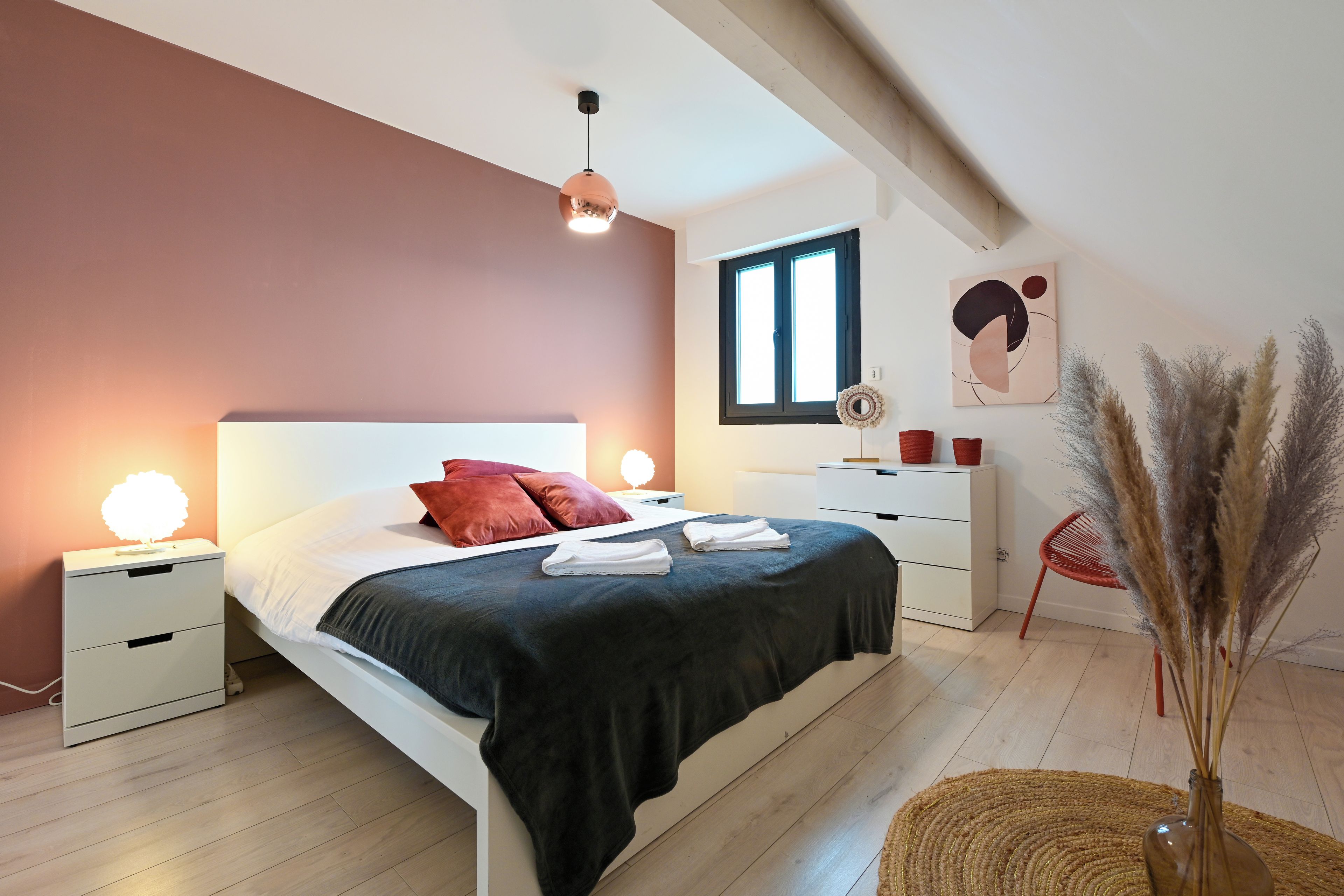 Un dormitorio moderno con una cama, mesitas de noche, una ventana y una obra de arte en la pared.
