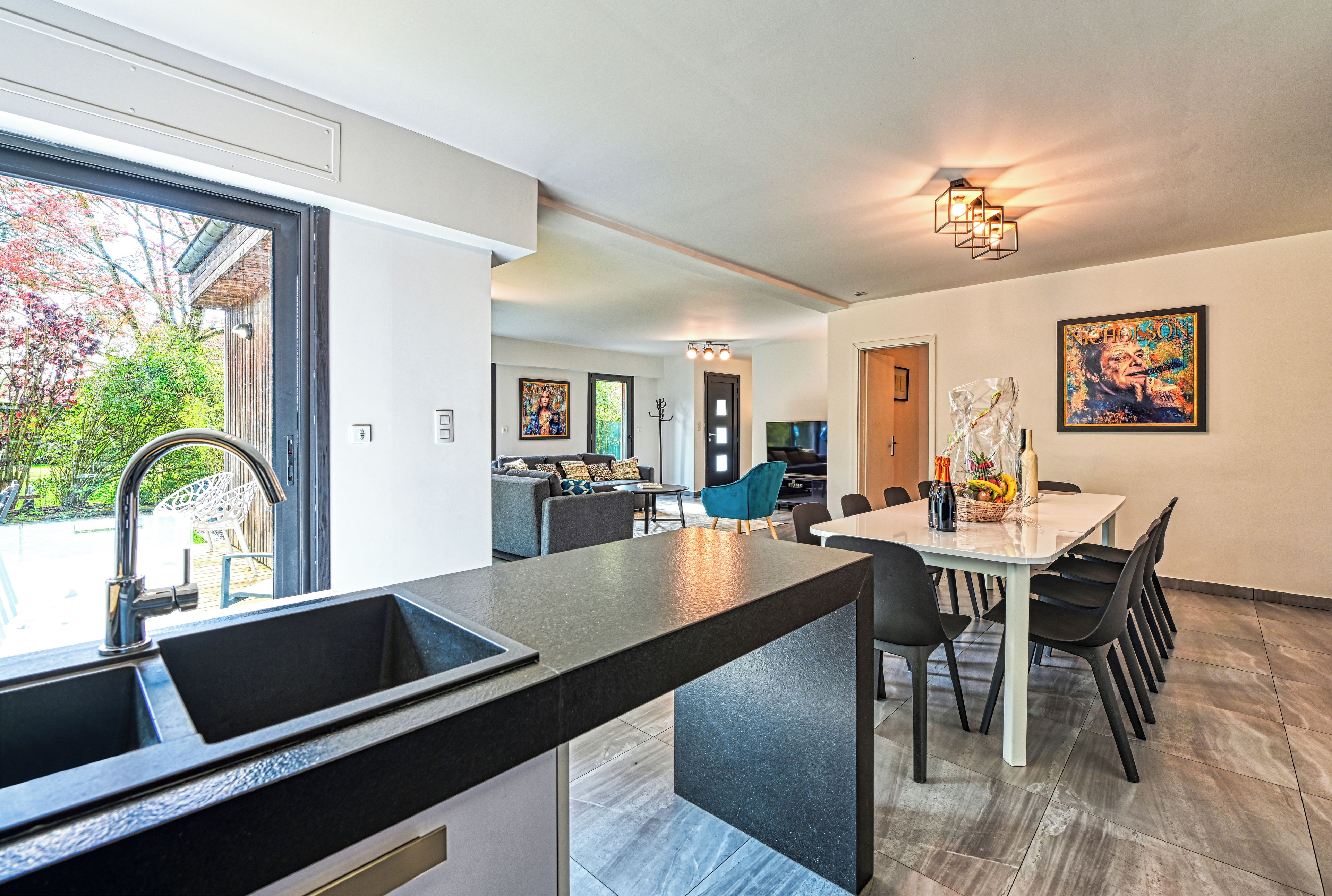 A modern kitchen with a large island, dining area with chairs, and a view of the outdoors.