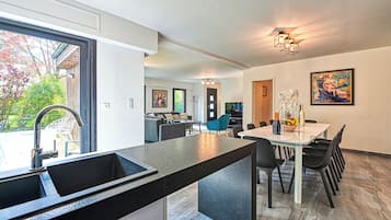 A modern kitchen with a large island, dining area with chairs, and a view of the outdoors.