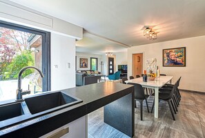 A modern kitchen with a large island, dining area with chairs, and a view of the outdoors. - Villa contemporaine 7 minutes du Centre de Lille (Marcq-en-Barœul)