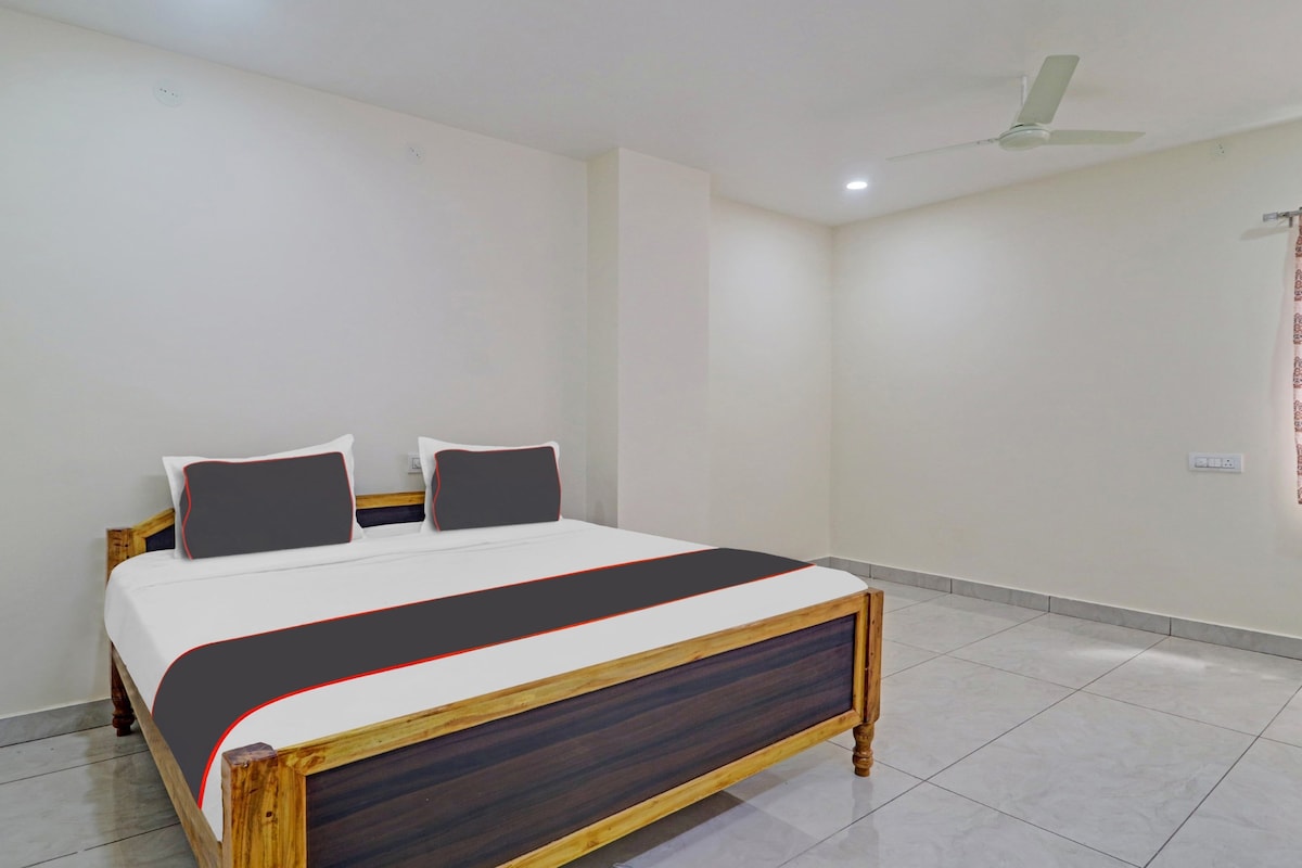 Un dormitorio con una cama, un ventilador de techo y una pared blanca lisa.