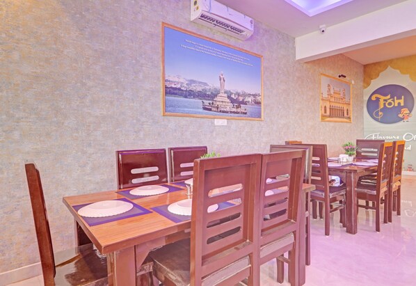 A dining area with wooden tables and chairs, a poster on the wall, and a ceiling fan.