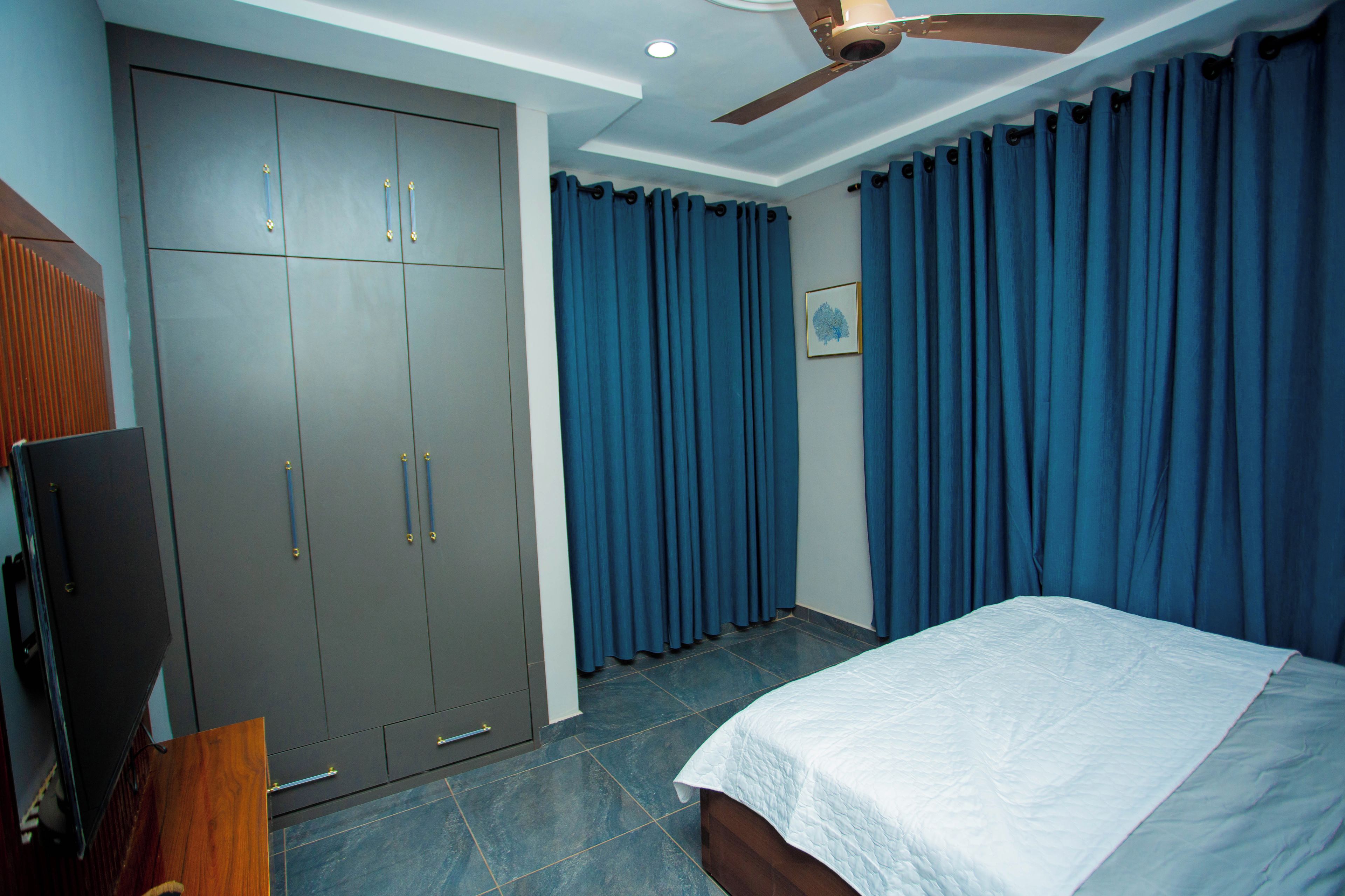 A bedroom with a bed, a wardrobe, and a ceiling fan.
