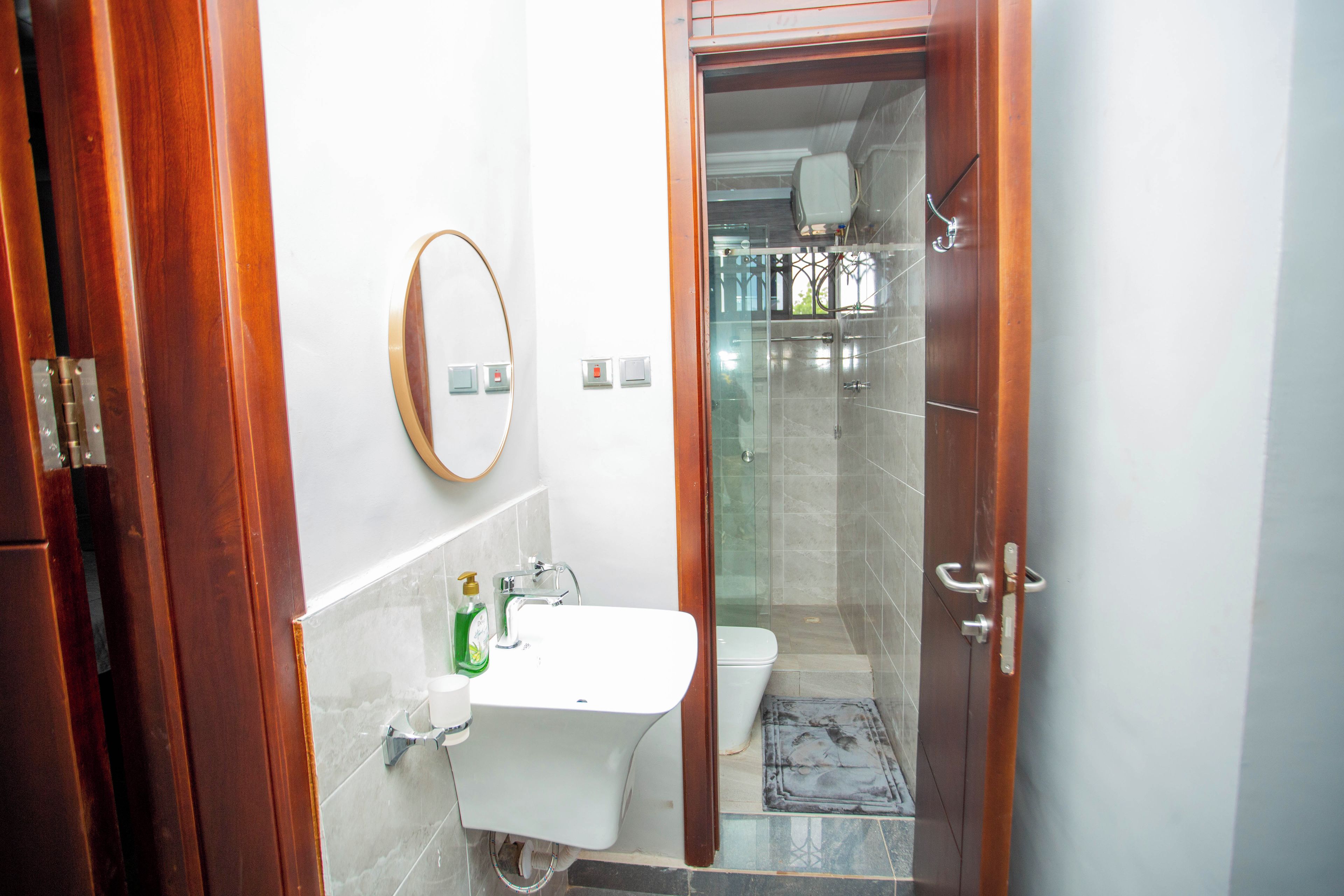 A bathroom with a wooden door, a white sink, a mirror, and a glass shower enclosure.