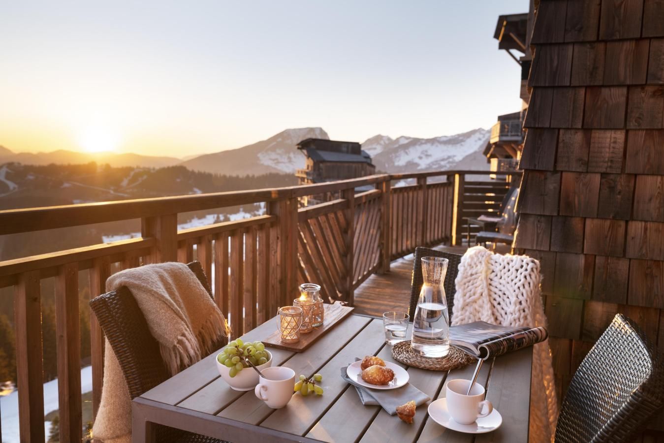 Una terraza de madera con una mesa preparada para una comida, con vistas a un paisaje montañoso.