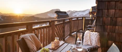 Una terraza de madera con una mesa preparada para una comida, con vistas a un paisaje montañoso.