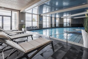 Ein Hallenbad mit Liegestühlen und Blick auf die verschneite Landschaft.