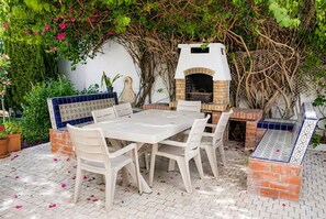 An outdoor patio with a brick oven, white table, and chairs. - sandra 32 (Tunis)