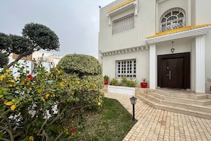 A two-story building with a white facade, a dark brown door, and a small balcony with yellow railings. - sandra 32 (Tunis)
