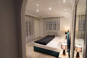 A modern bedroom with a bed, bedside lamps, and a large mirror. - sandra 32 (Tunis)