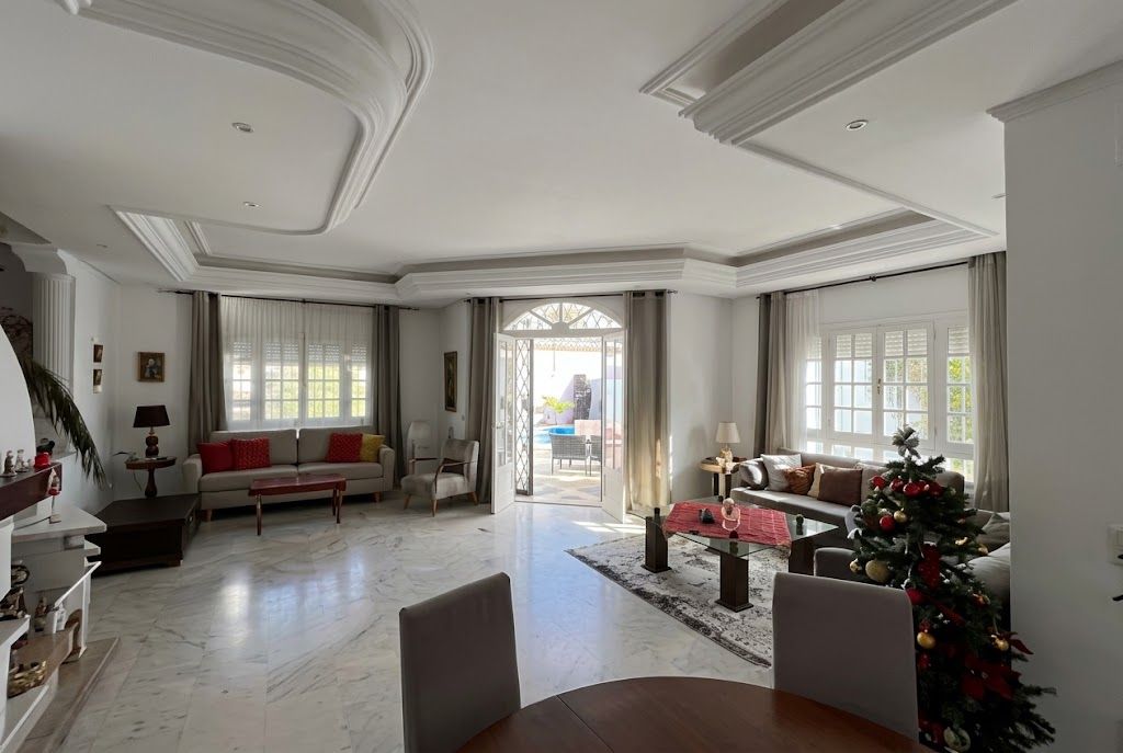 Un amplio salón con una mesa de comedor, sofás y un árbol de Navidad.