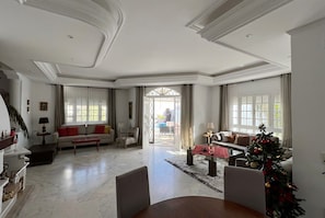 A spacious living area with a dining table, sofas, and a Christmas tree. - sandra 32 (Tunis)