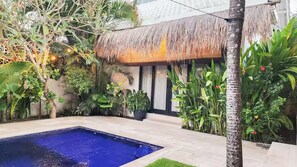 A pool area with a thatched roof structure, surrounded by lush greenery and potted plants. - Villa Drifter-Canggu Newly Renovated Private Villa (Kecamatan Kuta Utara)
