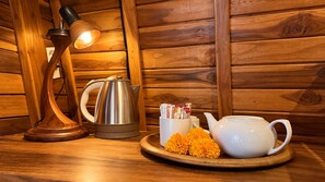 Una mesa de madera con una lámpara, una tetera, una taza y una bandeja con flores.