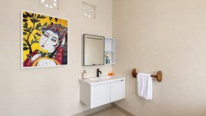 Un baño con un lavabo blanco, un espejo y un perchero para toallas.