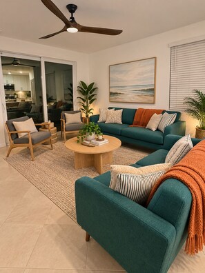 A living room with a teal sofa, a coffee table, and a ceiling fan. -  Gorgeous views !!! 3-bedroom condo in a golf community in lakewood Ranch. (Bradenton)