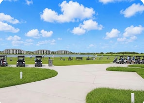 A golf course with a clear sky, a water body, and buildings in the background. -  Gorgeous views !!! 3-bedroom condo in a golf community in lakewood Ranch. (Bradenton)